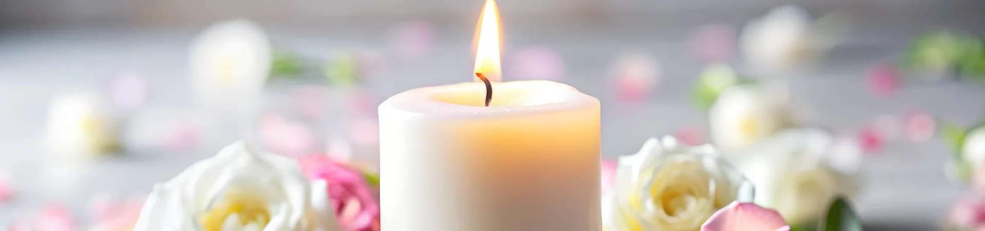 A lit candle and vibrant roses elegantly arranged on a wooden table.